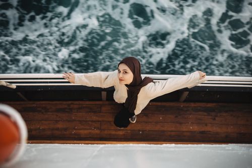 Free Woman with headscarf stretching arms on a ferry near Adalar, Istanbul, overlooking the sea. Stock Photo