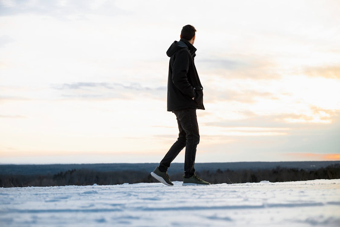 Man in Black Hooded Jacket and Pants Walking on Snow