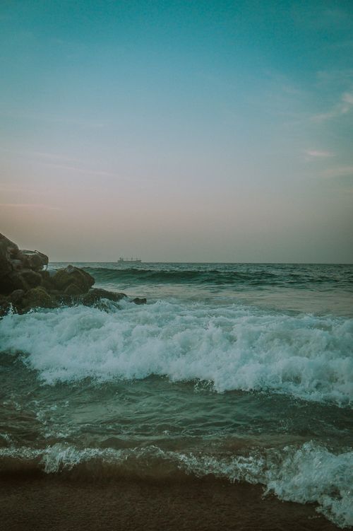 Free Soothing ocean waves gently crashing against rocks on a serene beach during twilight. Stock Photo