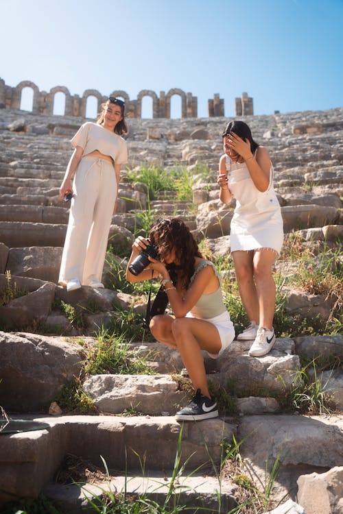 Three women taking pictures on the steps of an ancient building