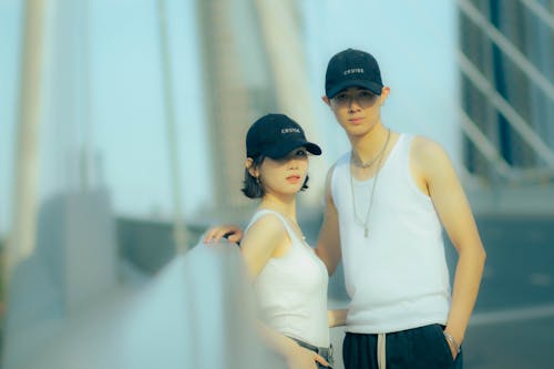 A couple wearing baseball caps on a bridge