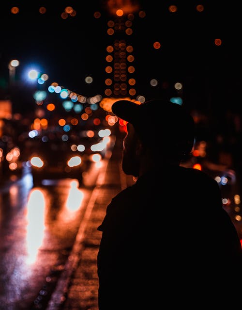 Gratuit Photographie De Silhouette D'homme Debout à Côté De La Route Avec Des Voitures Qui Passent Photos
