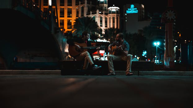 Two musicians play guitars on a night street in Eilat, Israel, creating a vibrant urban mood.