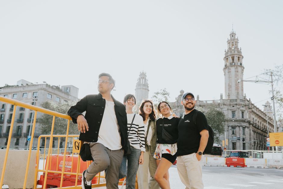 Grupo de amigos disfrutando de un día soleado en Barcelona cerca de un edificio histórico.
