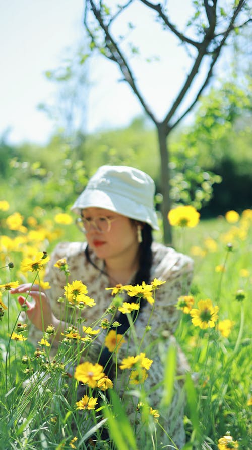 A woman in a hat and white shirt is looking at flowers