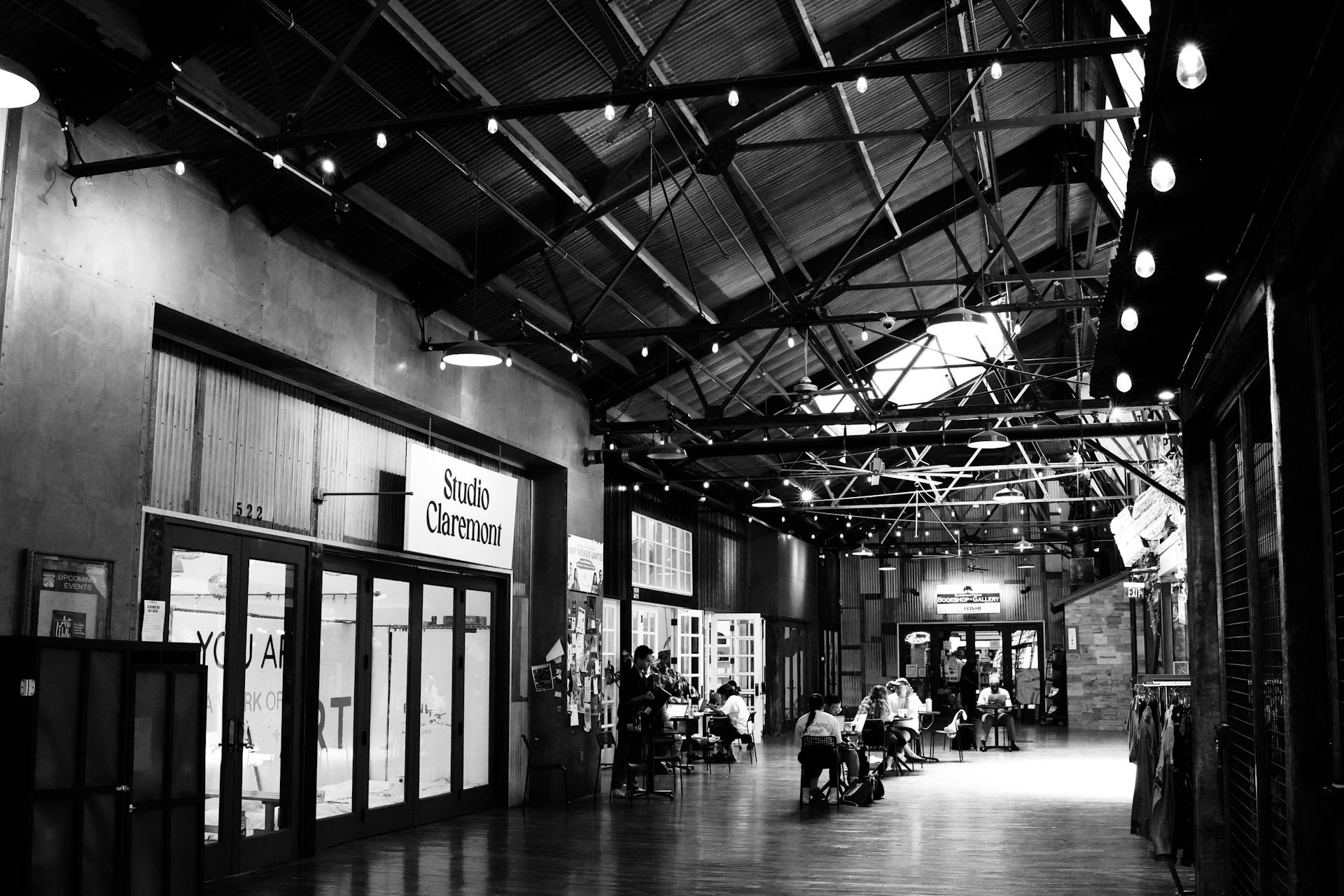 Black and white photo of Claremont Packing House interior featuring diners and architecture.