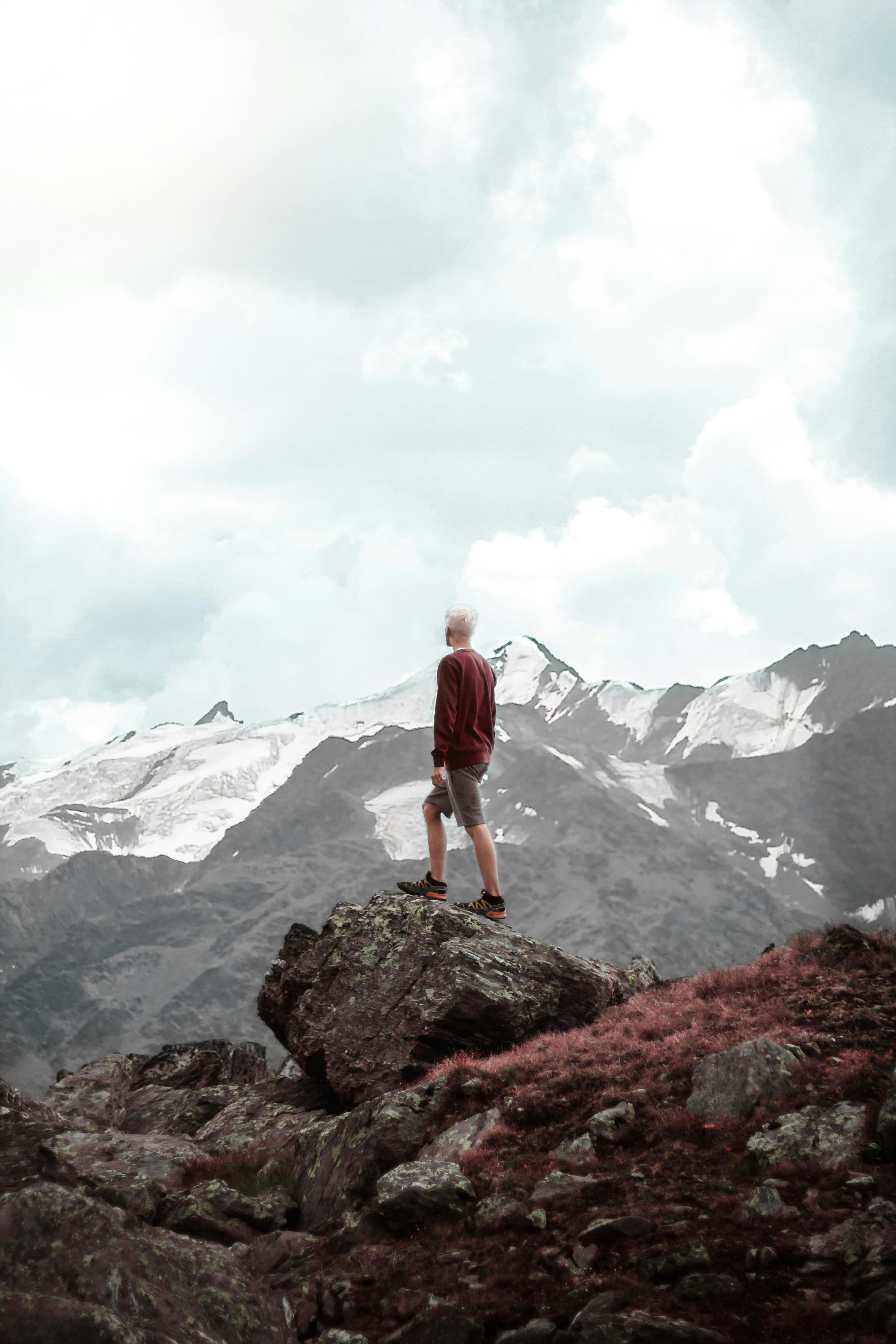 一名男子站在岩石上，俯瞰意大利博尔米奥的雪山