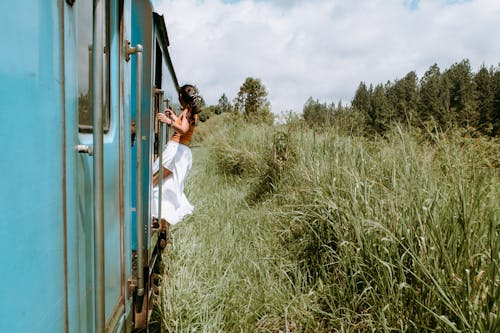 電車からぶら下がっている茶色のトップと白いスカートの女性の写真