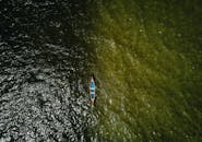 一张自上而下的航拍照片中，一艘独木舟正穿越碧绿而充满活力的湖泊，形成了令人惊叹的对比