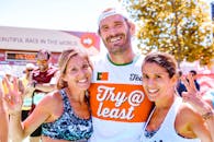 三名跑步者自豪地庆祝跑完马拉松，脸上带着微笑，做出和平手势