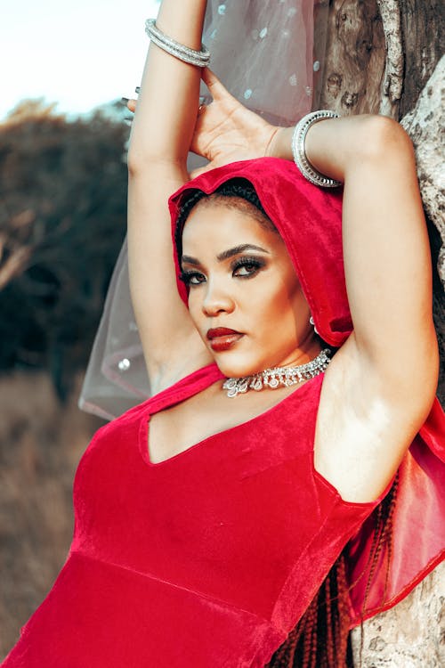 Woman in Red Dress and Veil Leaning on Tree