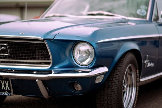 Detailed close-up of a vintage blue Ford Mustang showcasing its iconic design and headlight.
