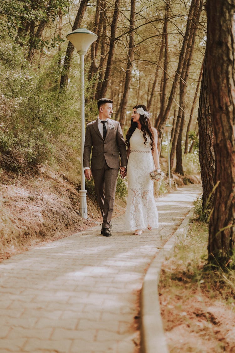 Photo Of Married Couple Walking Near Tall Trees