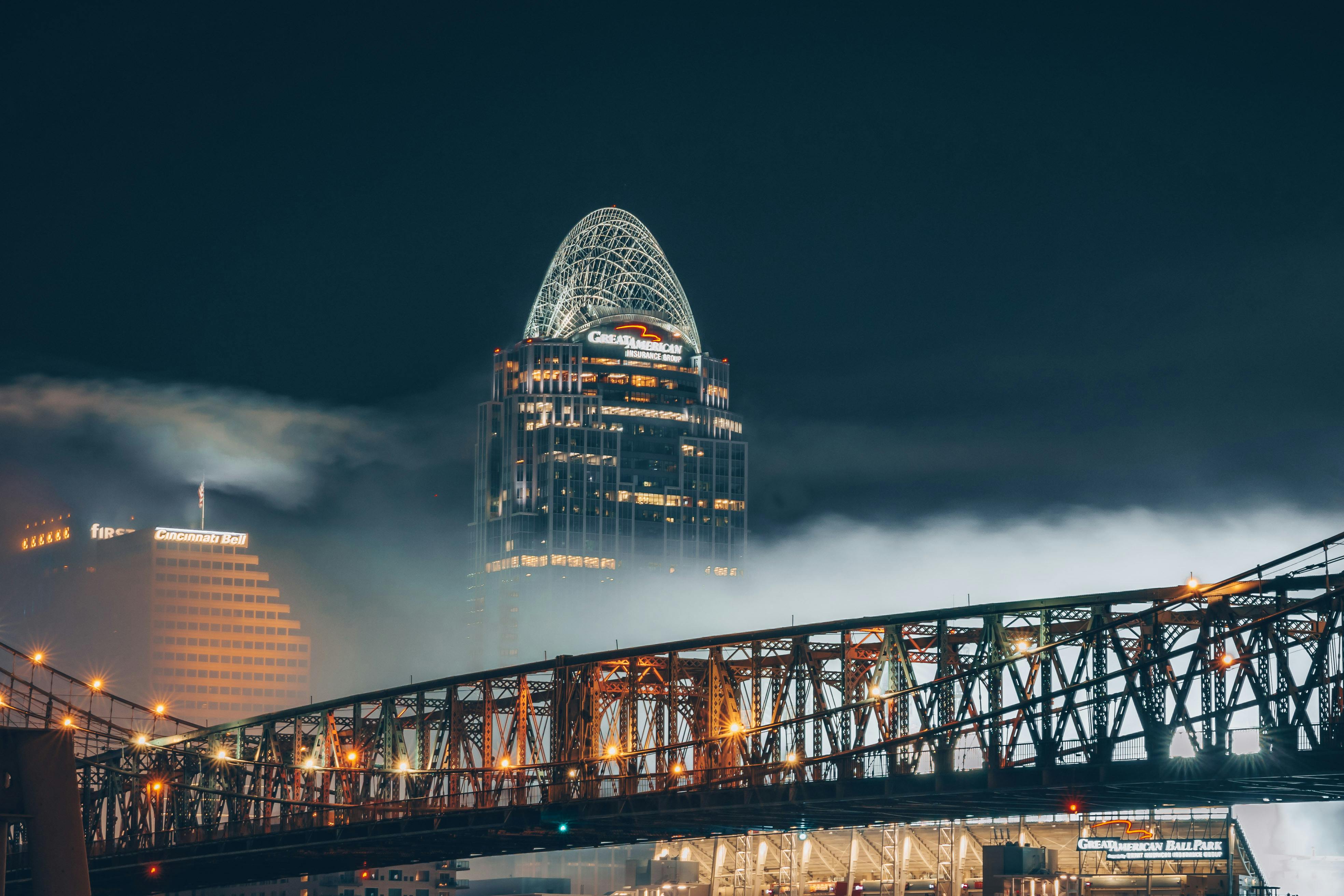 夜幕下，灯火通明的摩天大楼与雾气弥漫的桥梁，构成了戏剧性的城市景观