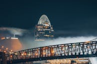 夜幕下，灯火通明的摩天大楼与雾气弥漫的桥梁，构成了戏剧性的城市景观