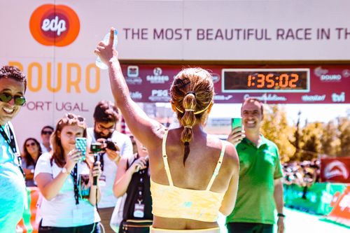 Free Runner celebrates at marathon finish line, surrounded by cheering audience and vibrant energy. Stock Photo