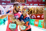 两名马拉松运动员在终点线快乐拥抱，庆祝他们的成就