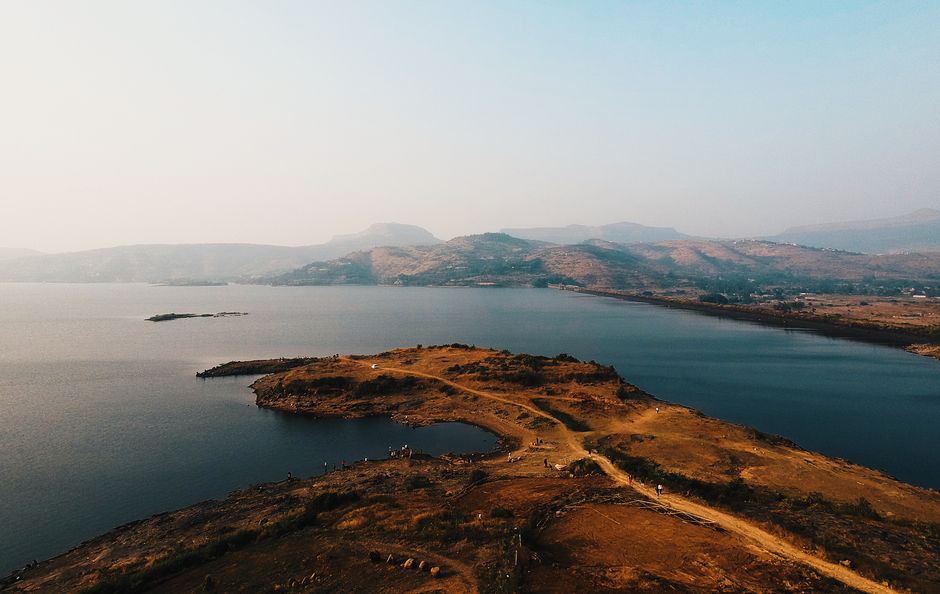 A stunning aerial view of a peaceful lake surrounded by rolling hills at dawn, showcasing natural beauty and tranquility.