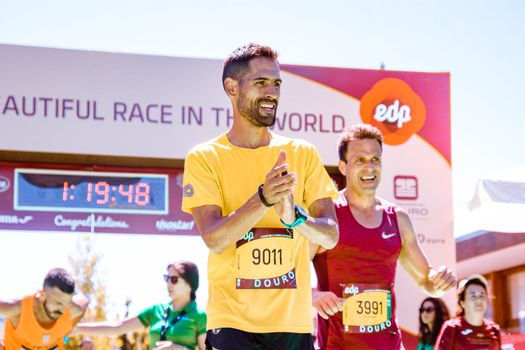Marathon runners celebrating their successful finish at a race event in bright daylight.