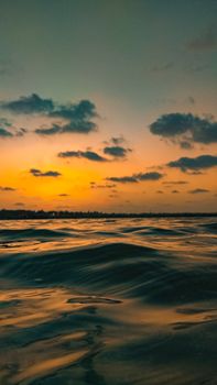 Fluffy clouds floating on picturesque colorful sunset sky reflecting in water of waving sea