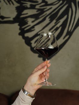 A close-up of a hand holding a red wine glass against an artistic backdrop, perfect for lifestyle and dining themes.