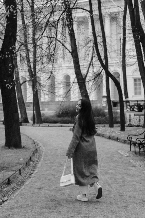 Free A young woman with long hair walks through a park, captured in a black and white photo. Stock Photo