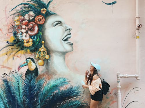 Side View Photo of Laughing Woman Standing Beside Graffiti Wall