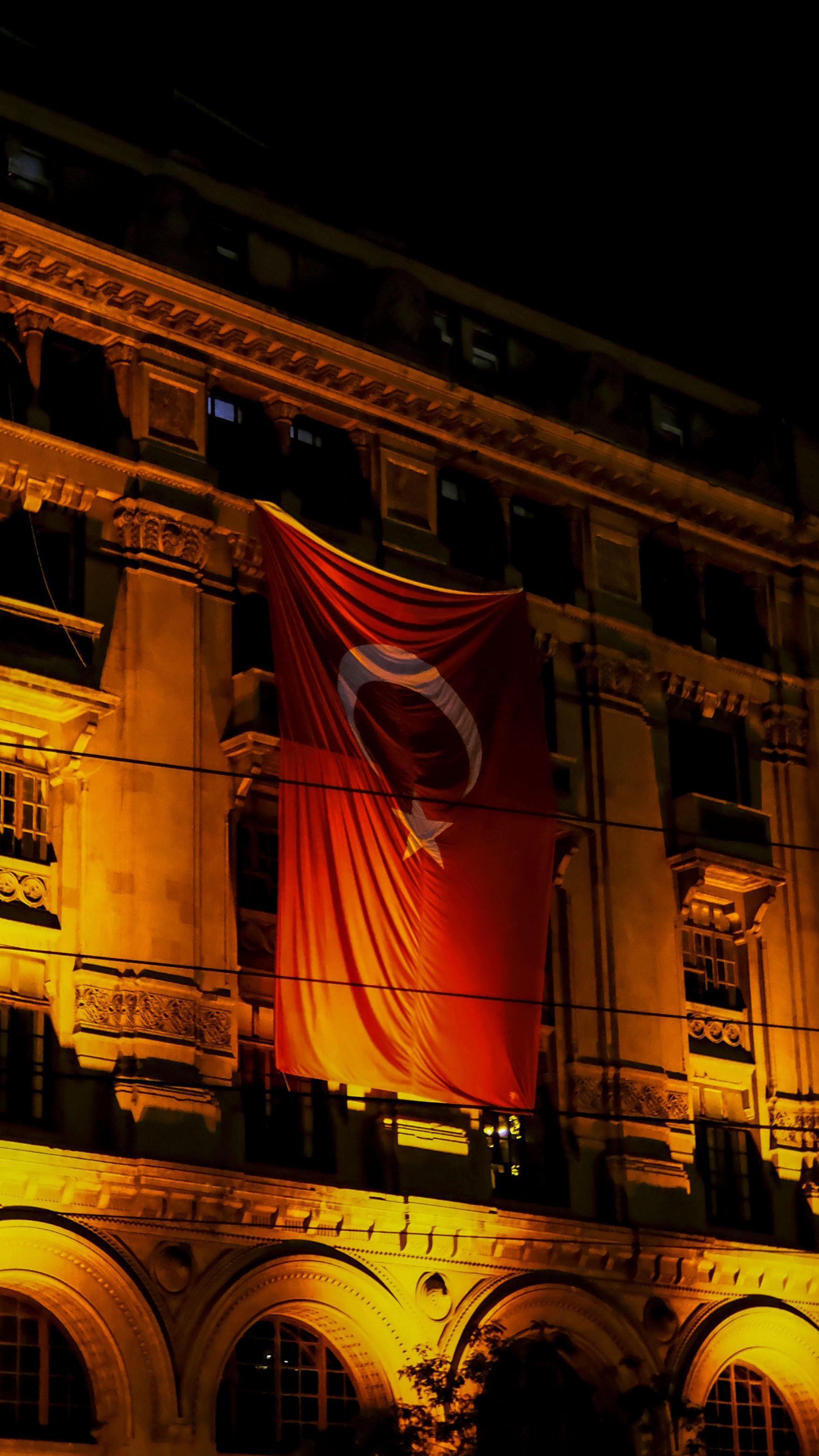 Turkish flag on a historic İstanbul building illuminated at night, showcasing cultural pride.