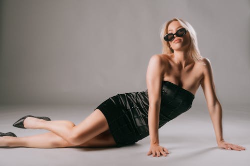 A blonde woman in a black dress laying on the floor