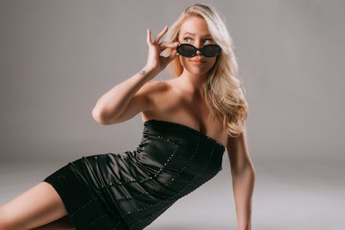 A blonde woman in a black dress and sunglasses