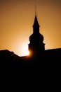The sun is setting behind a church steeple