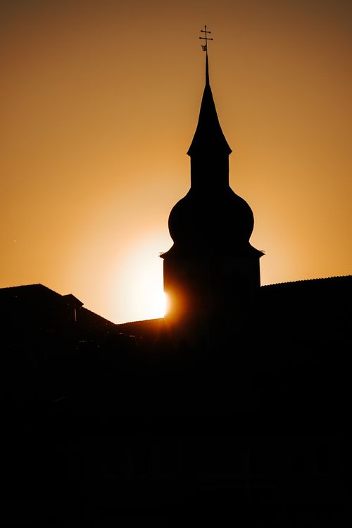 Free A church tower silhouette beautifully framed by the setting sun, creating a dramatic and peaceful scene. Stock Photo