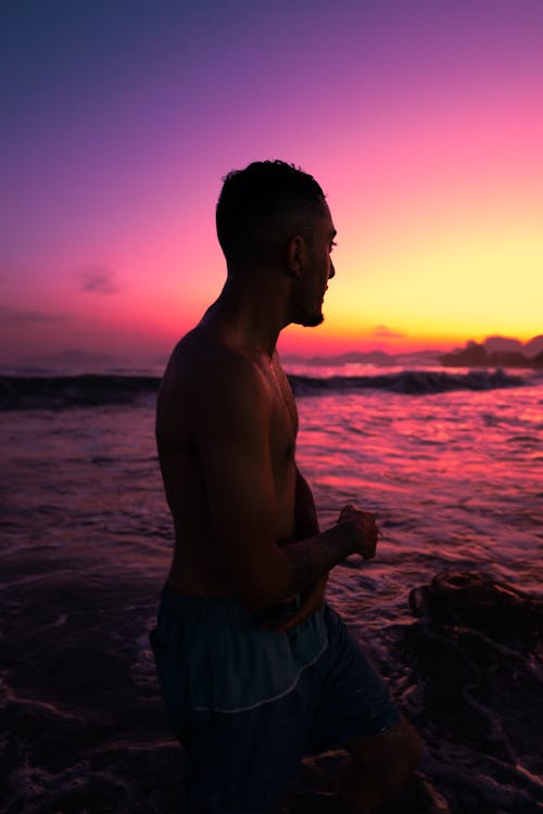 A man standing in the ocean at sunset