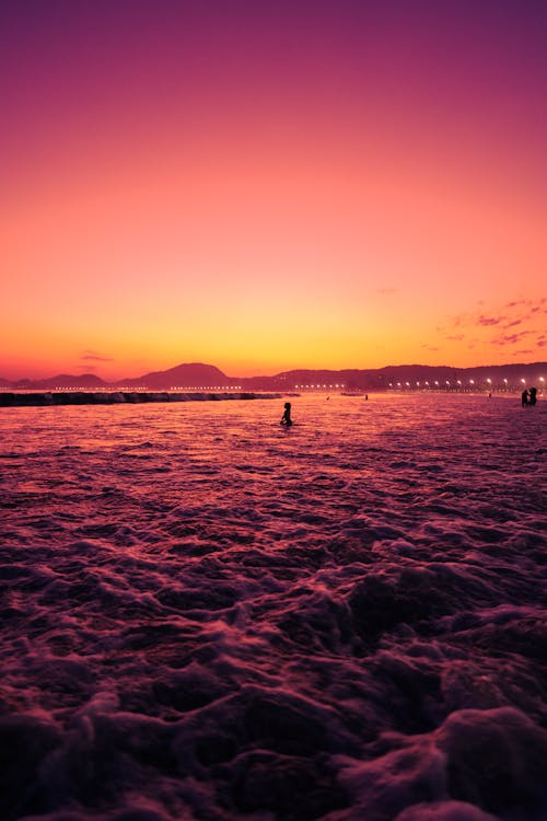 A person surfing in the ocean at sunset