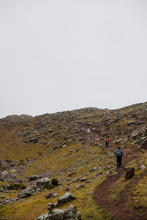 Free Three hikers ascending a rocky path in Cusco, Peru, surrounded by nature and mountains. Stock Photo