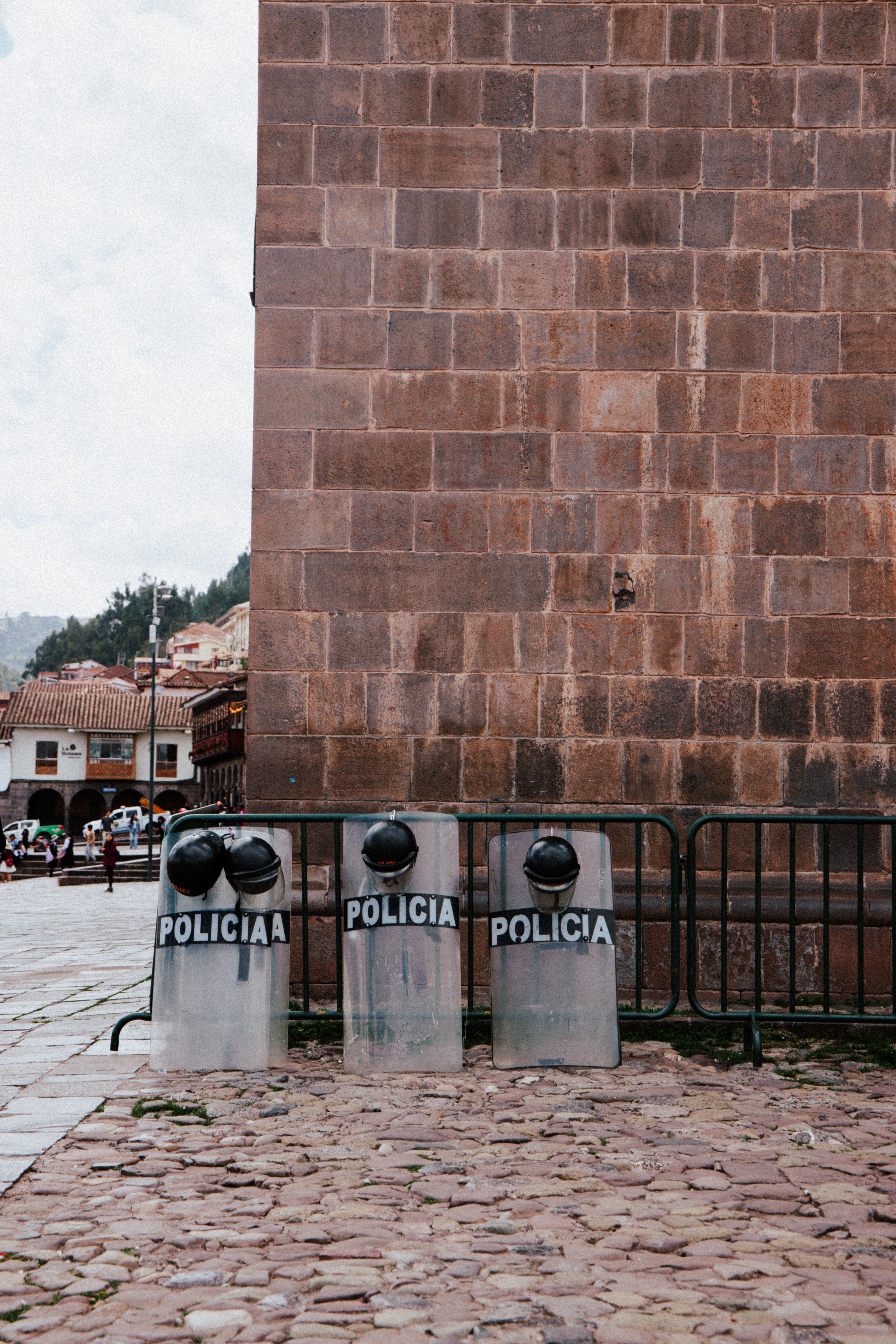 Riot shields labeled 'POLICIA' against a historic brick wall in Cusco, Peru.
