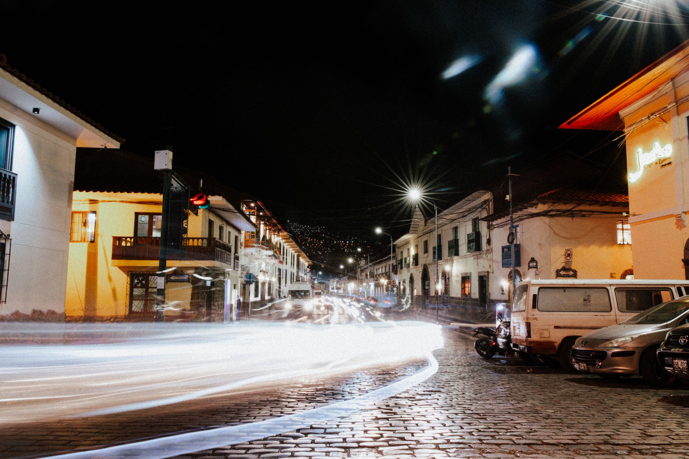 Blurred motion captures bustling night in Cusco city streets with vibrant urban lights.