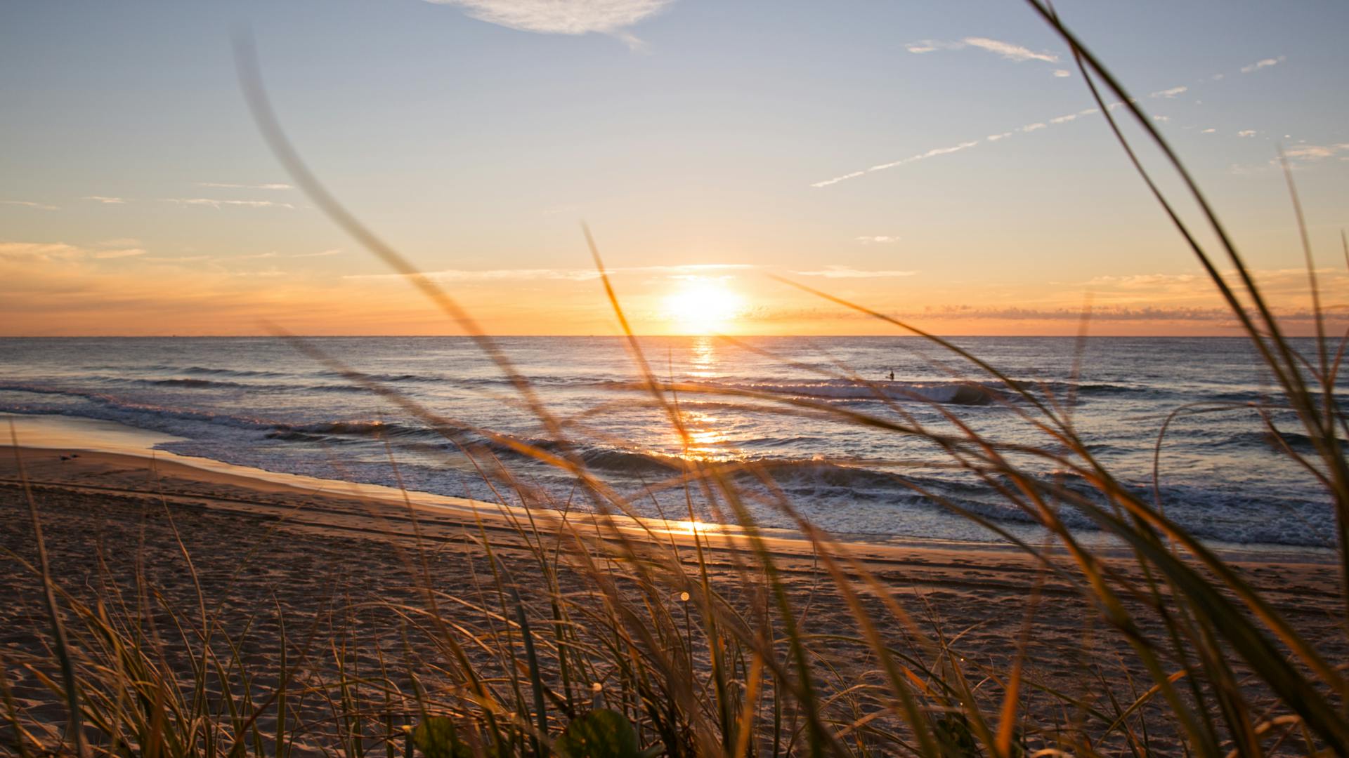 Golden sunset over a tranquil beach in Gold Coast, Australia with gentle waves and serene ambiance.