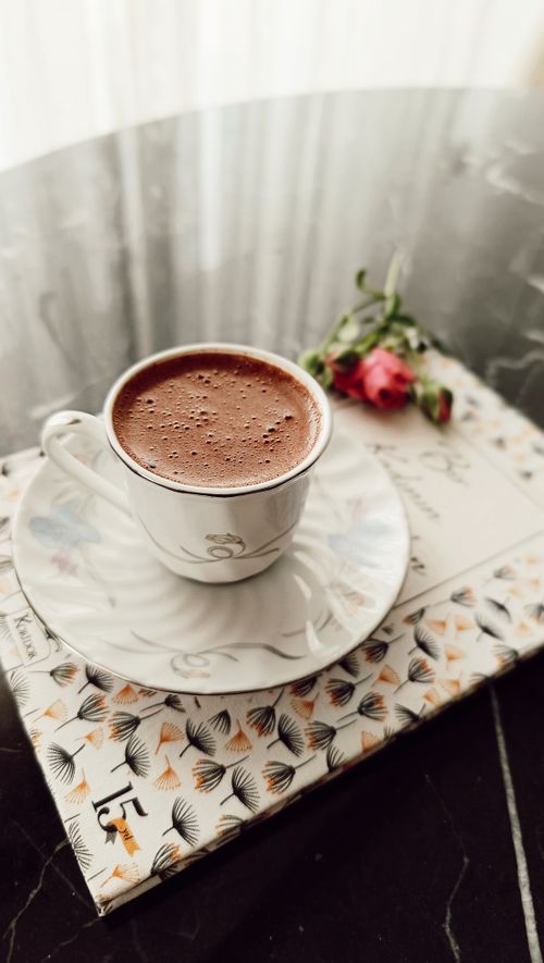 Free Close-up of a vintage coffee cup on a decorated surface with roses. Stock Photo