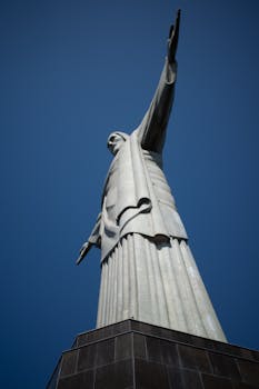 Low angle view of the iconic Christ the Redeemer statue under a clear blue sky in Rio de Janeiro.