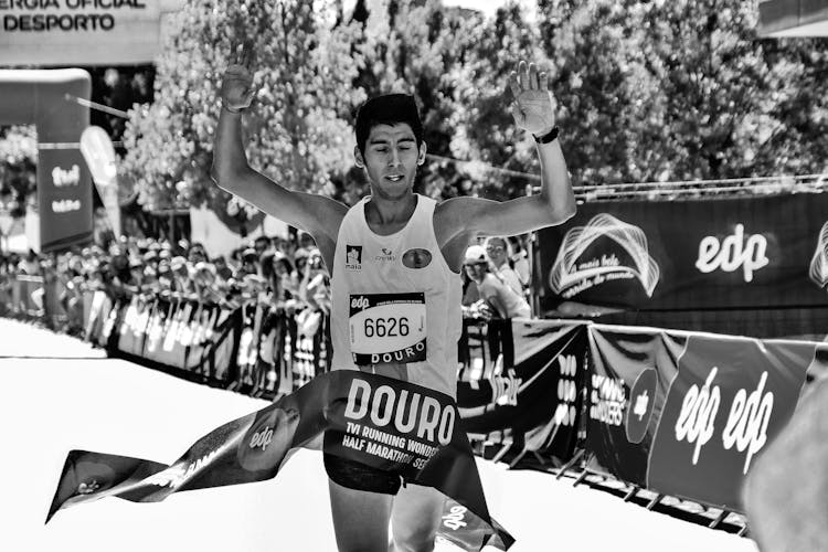 Grayscale Photo Of Man At The Finish Line Of A Marathon Race