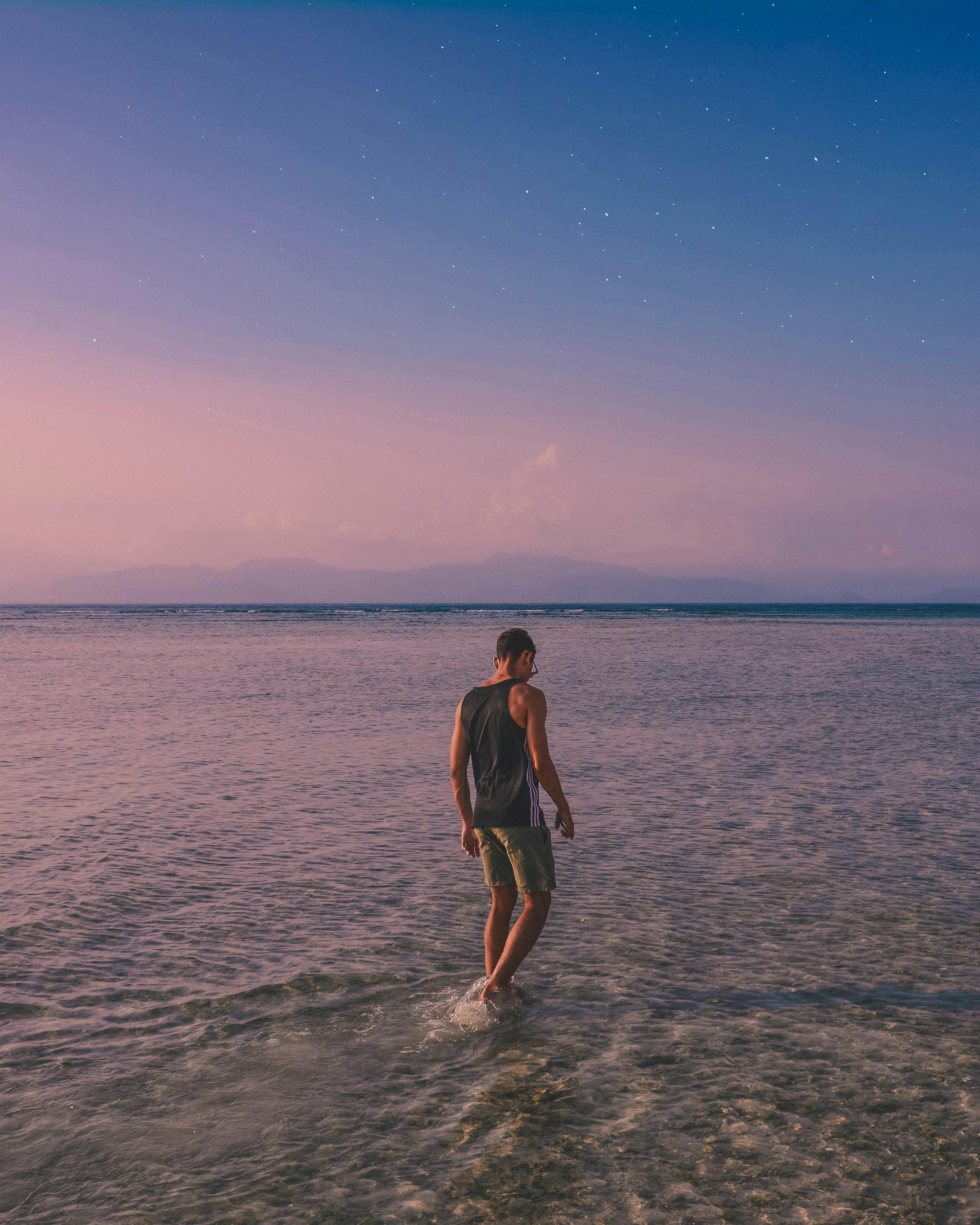 黄昏时分，一名男子独自漫步在巴厘岛宁静的海滩上，享受着海景的宁静