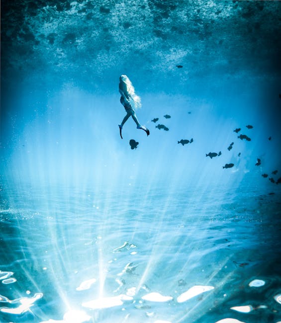 A captivating underwater scene featuring a lone diver illuminated by mystical blue light.