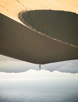 在超现实的沙漠场景中，一个孤独的人在沙丘上倒立