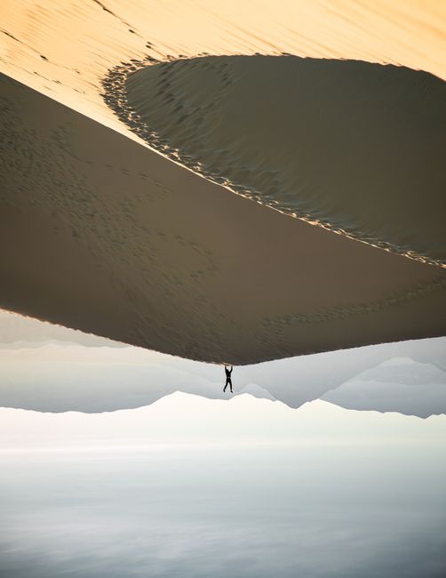 A surreal desert scene featuring a lone person performing a handstand on sand dunes.