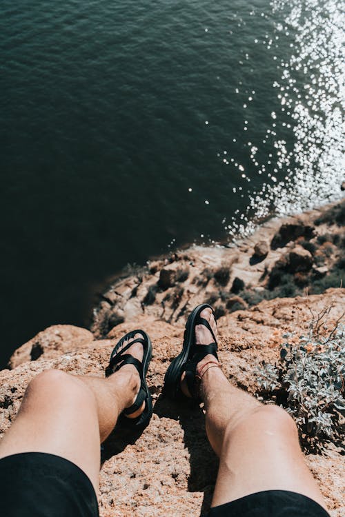 Faceless person resting on rocky cliff above ocean coast