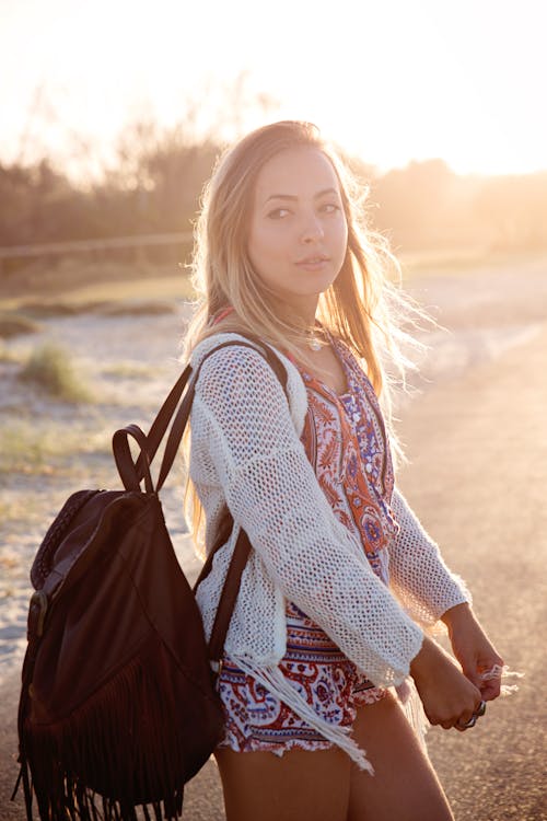 Woman Wearing Cardigan and Carrying Black Backpack While Standing Near Beach Side