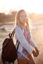 一位年轻女子背着背包，在澳大利亚昆士兰州的黄金海岸海滩上漫步，享受日落