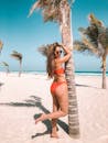 穿着红色比基尼的女人在热带海滩上享受阳光明媚的一天，那里有棕榈树和海景