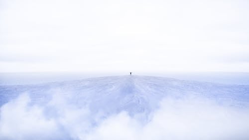 Person Standing On Top Of Mountain